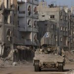 Sebuah kendaraan lapis baja melaju sementara bangunan-bangunan yang rusak terlihat di latar belakang, di tengah operasi darat yang sedang berlangsung oleh tentara Israel melawan kelompok Islamis Palestina, Hamas, di Jalur Gaza, 13 September 2024. REUTERS/Amir Cohen